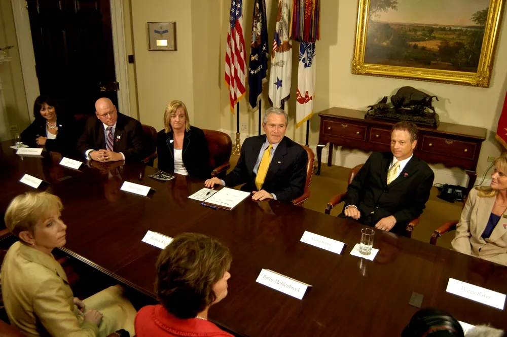 Military leaders meeting in a conference room with flags